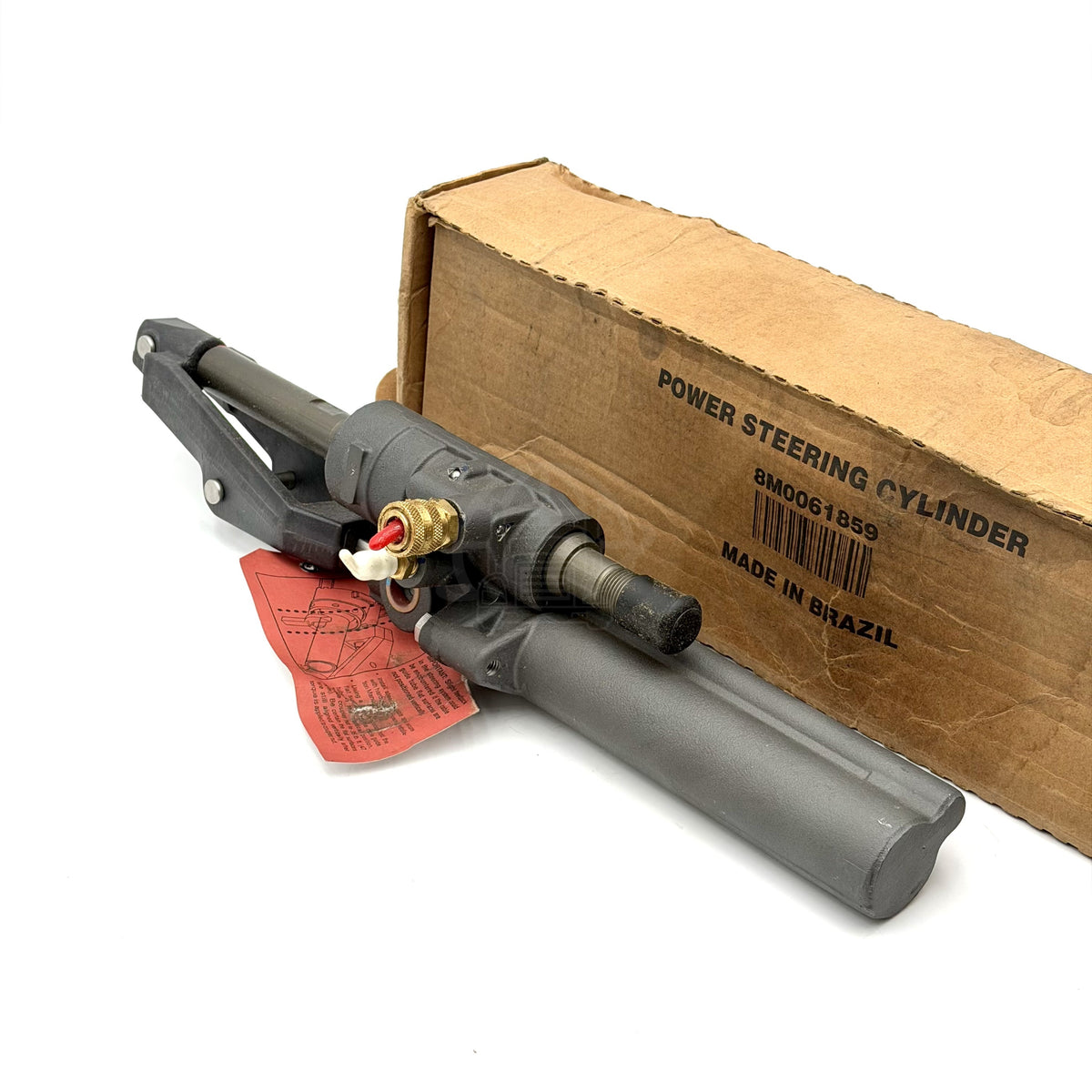 Three-quarter view of the 8M0063382 power steering cylinder next to its original cardboard packaging.